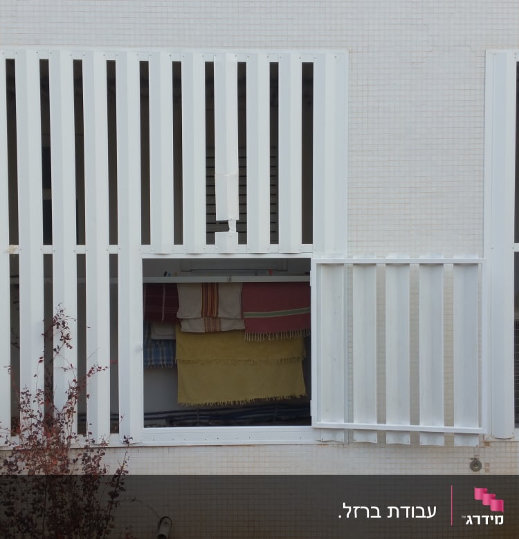 מסגרת חלון עם תריסים לבנים פתוחים